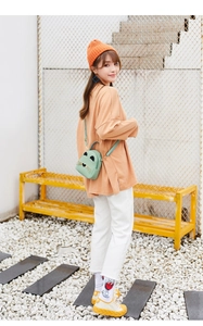Detail of mint green cartoon cat crossbody bag with adjustable strap on a female model