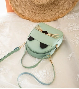 Detail of mint green cat-shaped crossbody bag with gold whiskers and leather texture