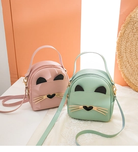 Detail of pink and mint green mini cat bags with gold hardware and adjustable straps