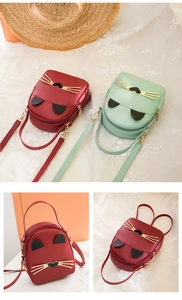 Detail of mini cat-shaped backpacks in burgundy and mint green with golden whiskers