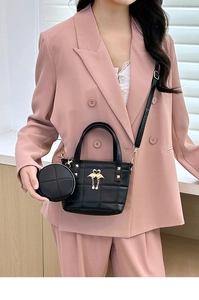 Detail of black quilted crossbody bag set with gold flamingo charm and round coin purse