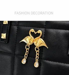 Detail of golden flamingo heart buckle with crystal pendant on black leather handbag