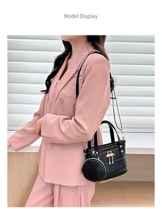 Close-up of black quilted shoulder bag set with golden swan buckle on pink blazer model