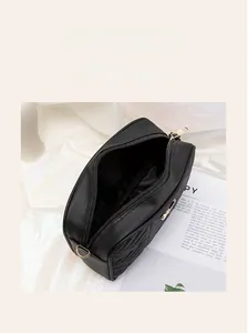 Detail view of the black quilted crossbody bag showing smooth zipper and interior space