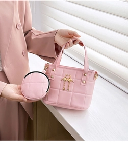 Detailed shot of pink quilted handbag with gold swan heart charm and matching pouch