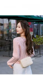Model wearing a beige quilted crossbody camera bag with elegant butterfly gold clasp