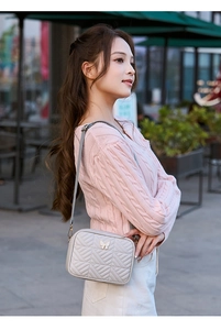 Detail of grey quilted camera bag with gold butterfly clasp and elegant embroidery