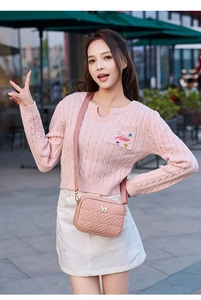 Close-up of pink quilted crossbody bag with butterfly buckle and wide strap on model