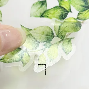 Detail showing hand peeling the translucent green leaf wall sticker with adhesive backing