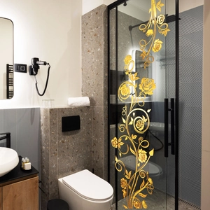 Close-up of golden floral vine wall decal on a modern glass bathroom shower door