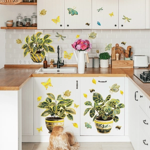 Detail of self-adhesive gold-trimmed plant and butterfly wall stickers on kitchen cabinets