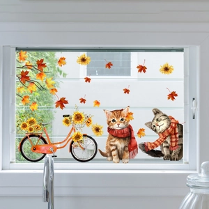 Detail of autumn window decals featuring cartoon cats, bicycles, and maple leaves on glass