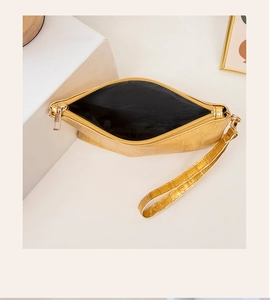 Detailaufnahme einer goldenen Clutch mit Krokodilprägung, Goldreißverschluss und Schlaufe