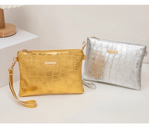 Detailansicht der goldenen und silbernen Clutch-Taschen mit Krokoprägung und Metalleffekt