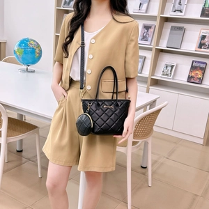 Elegante borsa trapuntata nera con logo dorato e mini pochette su una modella