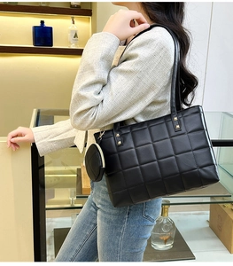 Detail of black quilted tote bag with golden studs and a small round coin purse charm