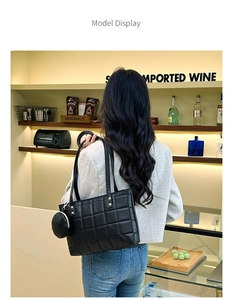 Detail of black quilted tote bag with a round mini pouch shown in a lifestyle scene