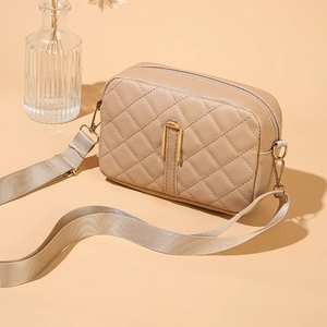 Dettaglio borsa a tracolla trapuntata beige con fibbie dorate e tracolla larga in tessuto