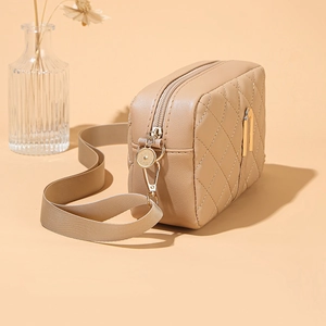 Dettaglio borsa a tracolla trapuntata beige con finiture dorate e tracolla in tessuto chic