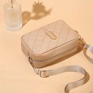 Dettaglio della borsa fotografica beige trapuntata con finiture dorate e tracolla