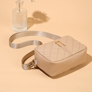 Dettaglio della borsa a tracolla trapuntata beige con chiusura a U dorata e tracolla