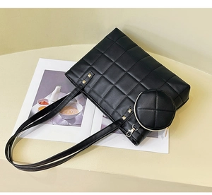 Close-up of black quilted tote bag with matching round coin purse and gold studs