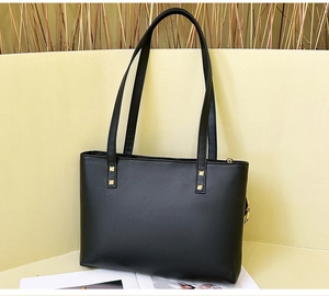 Close-up of black quilted tote bag with golden rivets and top zipper closure