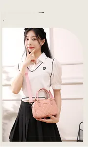 Close-up of pink quilted shell bag with golden logo and matching wide fabric strap