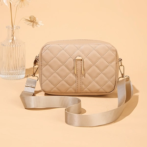 Dettaglio borsa a tracolla beige trapuntata con tracolla larga e cerniera dorata lucida