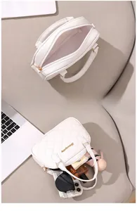 Interior storage capacity view of a white quilted shell bag with daily essentials inside