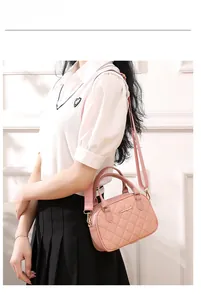 Detailed view of pink quilted PU leather handbag with gold metal logo and wide strap