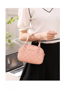 Detailed view of pink quilted shell bag featuring dual top handles and metal logo plate