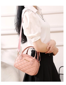 Close-up of pink quilted shell bag featuring gold logo and detachable shoulder strap