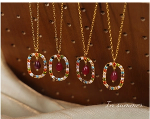 Detailed view of golden boho necklace featuring red teardrop pendant and zircon inlay