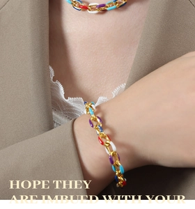 Detail eines farbenfrohen Emaille-Gliederarmbands an einem Modell in khakifarbenem Blazer