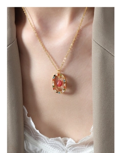 Detail of elegant gold titanium necklace with colorful stones and red agate teardrop pendant