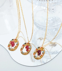 Detailed shot of gold necklaces with multi-color rhinestones and red pear-shaped pendant