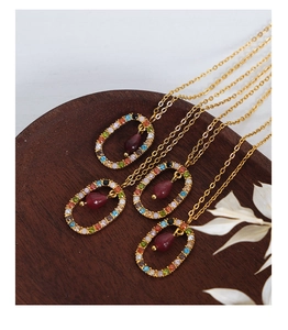 Detail of four gold necklaces with colorful crystals and wine red teardrop pendants