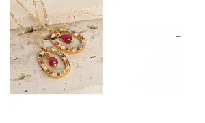 Macro detail of gold oval pendant with CZ stone pavé and red agate teardrop drop