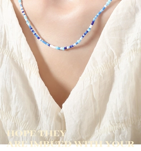 Detail of handcrafted blue gradient beaded necklace worn with elegant pleated attire