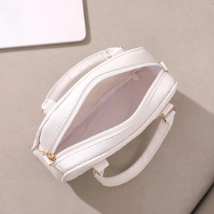Minimalist white shell handbag with gold zipper and dual handles shown from a 45-degree angle