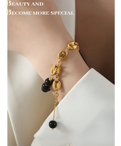 Detail of gold knot chain bracelet with black agate beads on female model wrist
