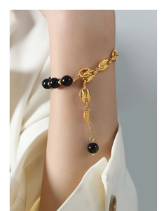 Detail of coffee bean link chain bracelet with black beads and gold clasp closure