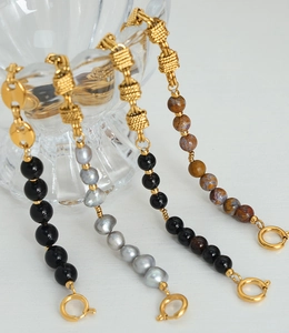 Detail of brass bracelets featuring knot chains with freshwater pearls and agate stones