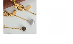 Macro detail of vintage gold chain bracelet featuring baroque pearl and brown agate charms