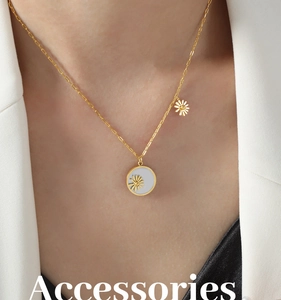 Detail of gold daisy necklace with white shell pendant worn with professional attire