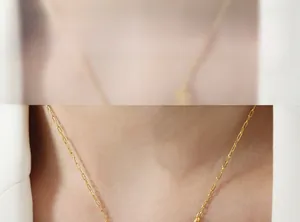 Detail of 18k gold plated paperclip chain necklace with a shell daisy pendant on a model