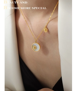 Close-up of gold daisy pendant necklace with mother of pearl inlay on a white blazer