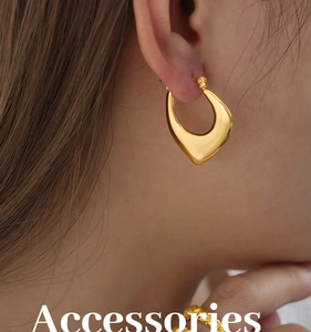 Close-up of elegant polished gold handbag-shaped earrings and matching twisted ring