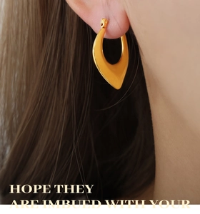 Detail of chunky gold water drop earring on model showcasing polished steel finish